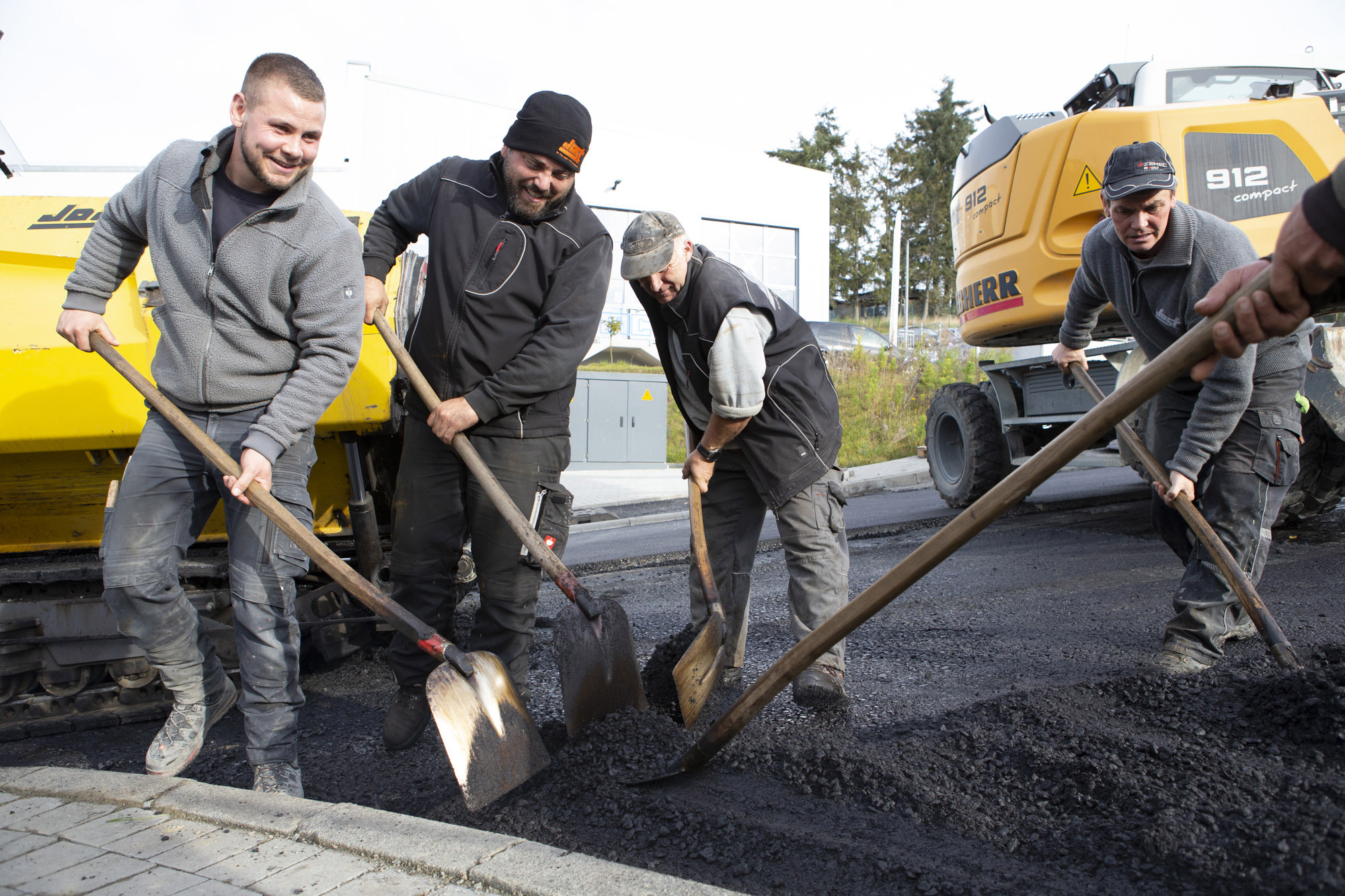 Gemeinsam schnell vorankommen: Mitarbeiter von Jost Straßenbau beim Teeren einer Straße.